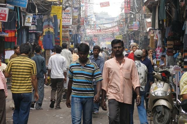 A crowded street in Main Bazaar, Paharganj, with pedestrians, scooters and shop signs
