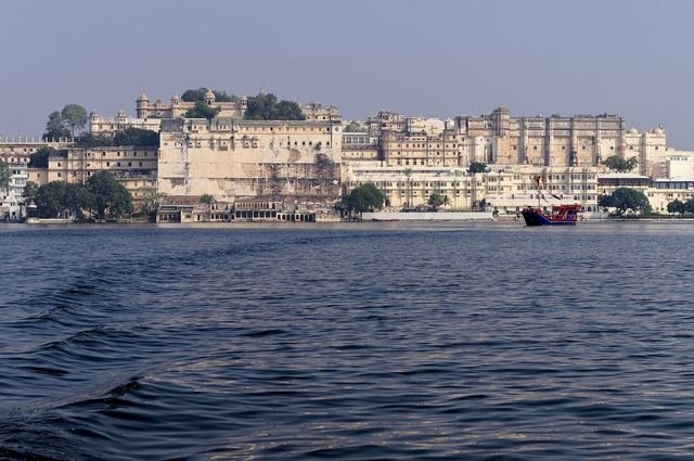 The long white facade of the City Palace in Udaipur seen across the water of Lake Pichola
